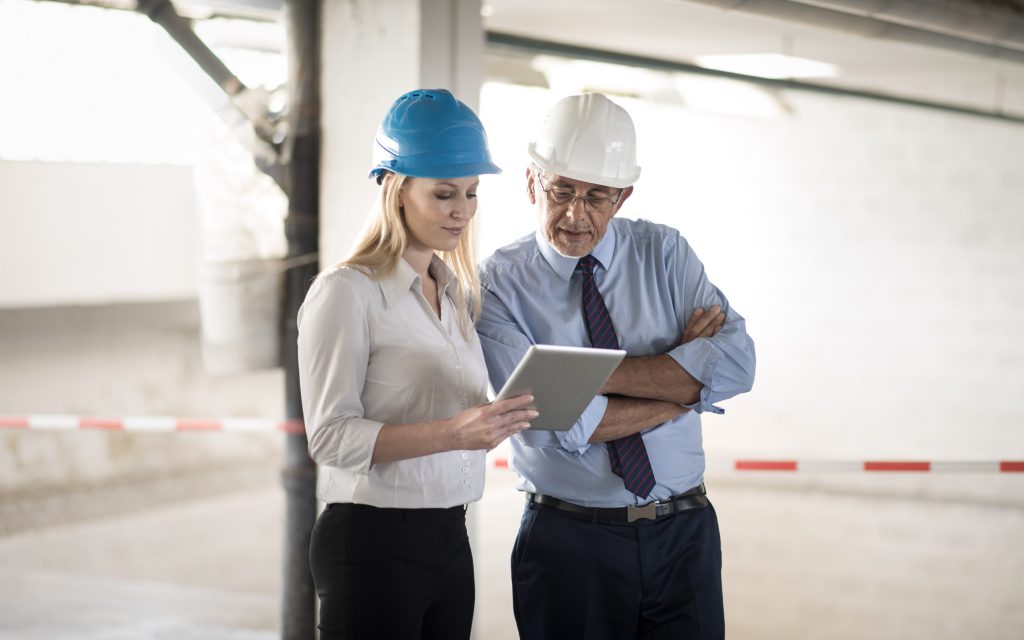 Deux professionnels du bâtiment consultent une tablette sur le chantier