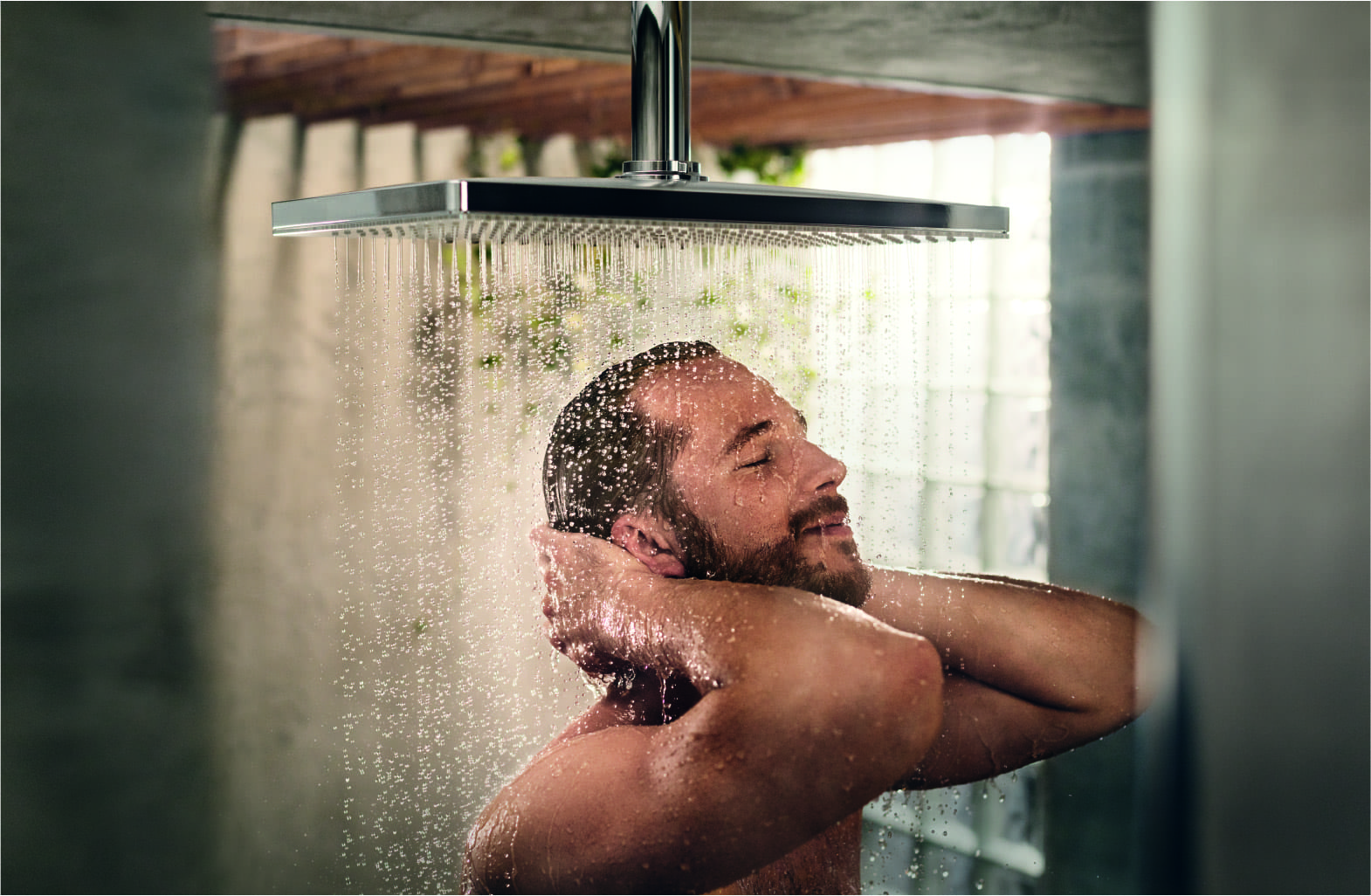 Homme qui se douche dans la salle de bains avec une douche encastrée Hansgrohe