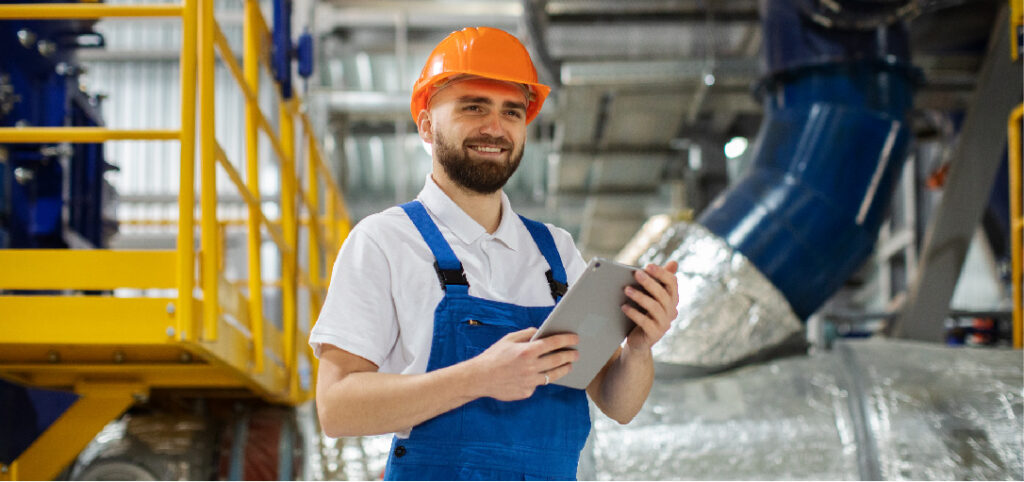 Professionnel du bâtiment avec un casque de chantier orange et une tablette tactile en mains