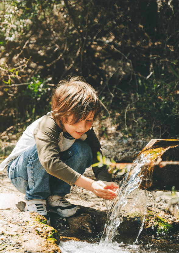 Petit garçon avec de l'eau illustrant les engagements écologiques de SFA